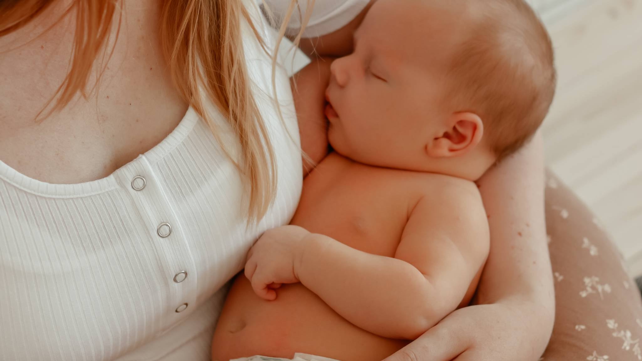 Mother holding her newborn baby close in a moment of safety and care, representing the values of Nordisk Family